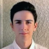 A young man with dark hair and wearing a white shirt.